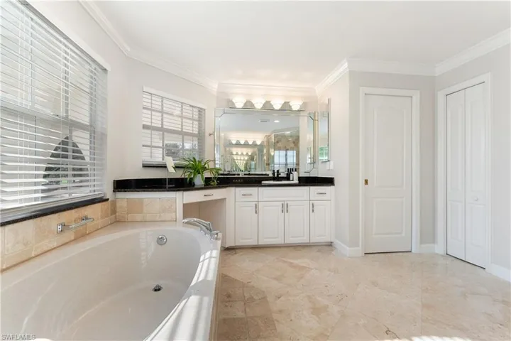 Bathroom with vanity, a garden tub, and crown molding