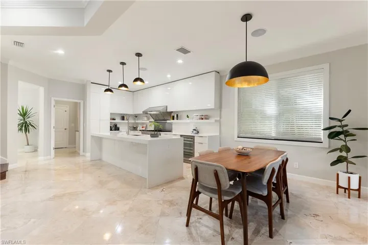 Dining space featuring ornamental molding, wine cooler, and recessed lighting
