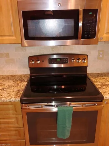 Kitchen view of appliances with stainless steel finishes, light stone counters, and tasteful backsplash