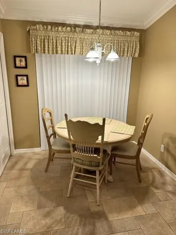 Dining room featuring crown molding, a chandelier, and stone tile floors