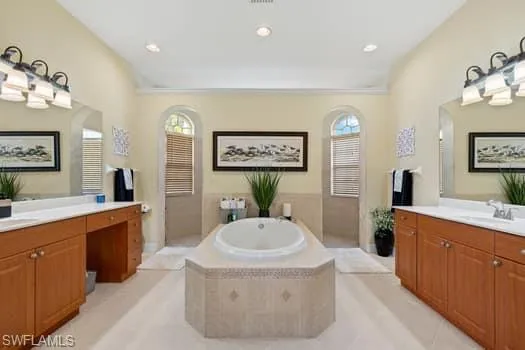 Bathroom featuring tile patterned flooring, vanity, and a relaxing tiled tub