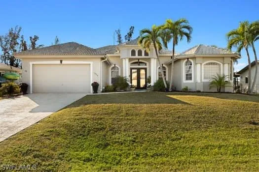 View of front of home with a garage, a front yard, and french doors