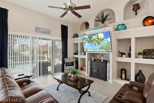 Living room with built in shelves, ceiling fan, and a towering ceiling