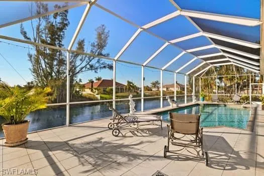 View of pool with a water view, a patio, and glass enclosure