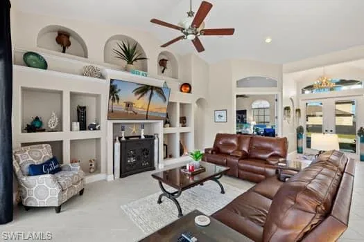 Living room with built in shelves, ceiling fan, and french doors