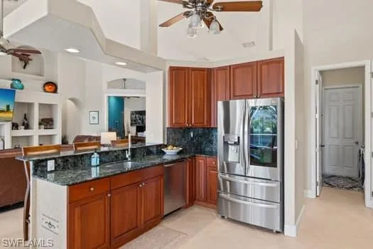 Kitchen with sink, a kitchen bar, dark stone counters, kitchen peninsula, and stainless steel appliances