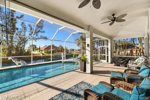View of pool with a patio, an outdoor hangout area, ceiling fan, and glass enclosure