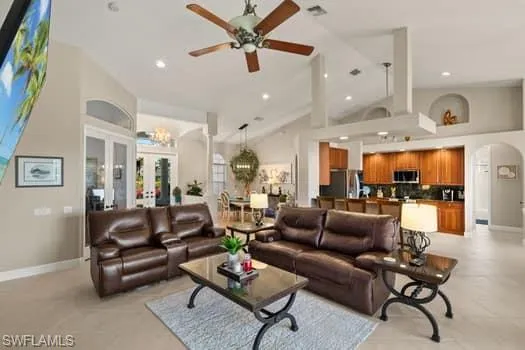 Living room with ceiling fan, high vaulted ceiling, and french doors