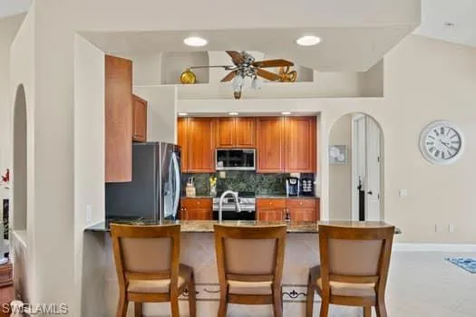 Kitchen featuring a breakfast bar, sink, backsplash, kitchen peninsula, and stainless steel appliances