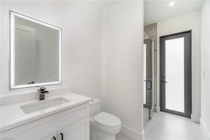 Bathroom featuring vanity, an enclosed shower, tile patterned flooring, and toilet