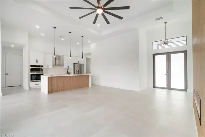 Unfurnished living room with sink, french doors, light tile patterned floors, a raised ceiling, and a towering ceiling
