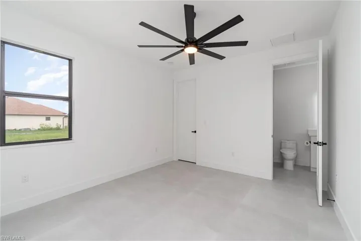 Unfurnished bedroom featuring ensuite bathroom, ceiling fan, and light tile patterned floors