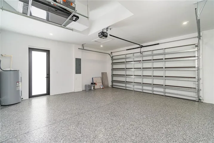 Garage with a garage door opener, water heater, and electric panel