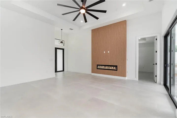 Unfurnished living room with a fireplace, a tray ceiling, ceiling fan, and a towering ceiling