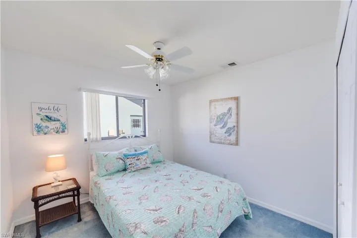 Carpeted bedroom with ceiling fan and baseboards