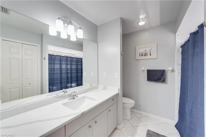 Full bathroom with a closet, a shower with shower curtain, vanity, and light tile patterned floors