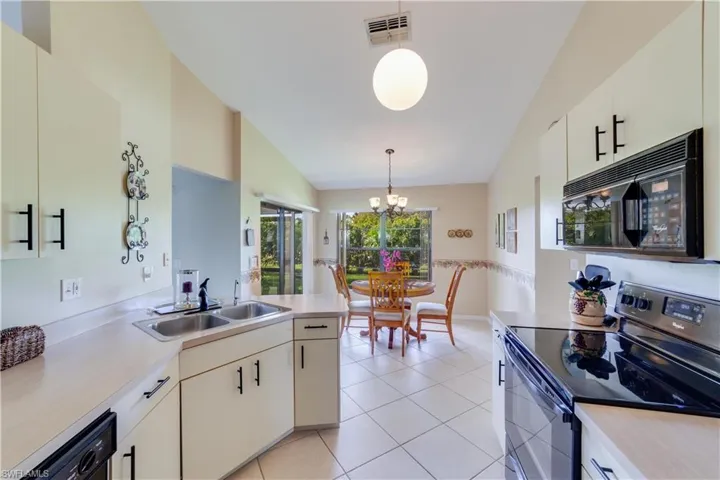 Kitchen featuring black appliances, light countertops, a chandelier, a peninsula, and white cabinets