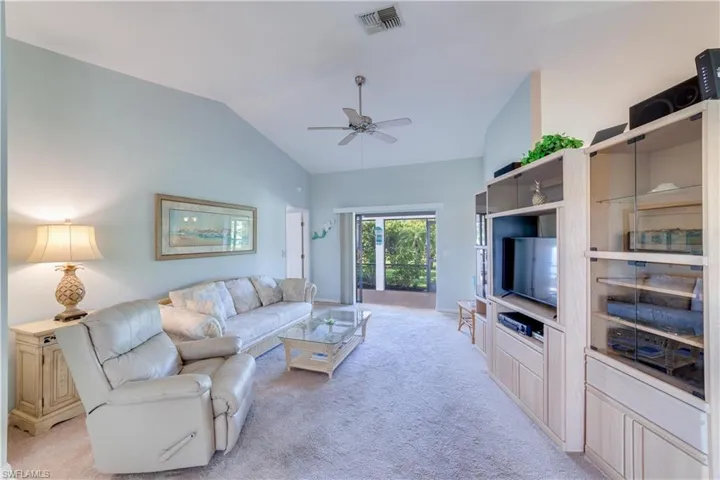 Living room featuring light colored carpet, lofted ceiling, and a ceiling fan