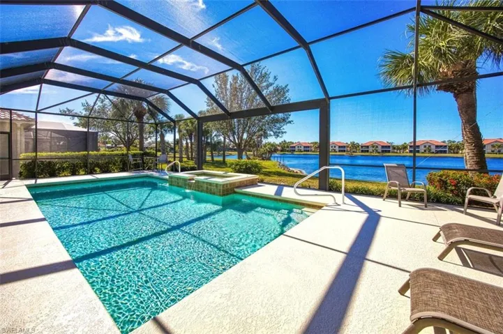 View of swimming pool with a lanai, an in ground hot tub, a patio, and a water view