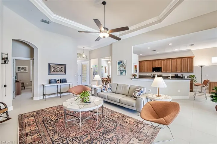 Living room featuring a raised ceiling, ornamental molding, and light tile patterned floors