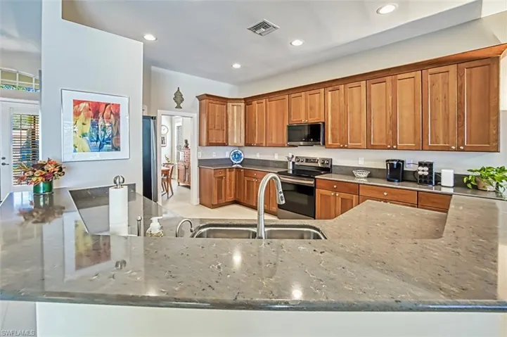Kitchen featuring appliances with stainless steel finishes, light stone countertops, sink, and kitchen peninsula