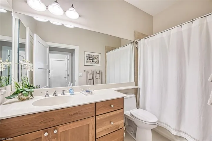 Bathroom featuring vanity, toilet, and curtained shower