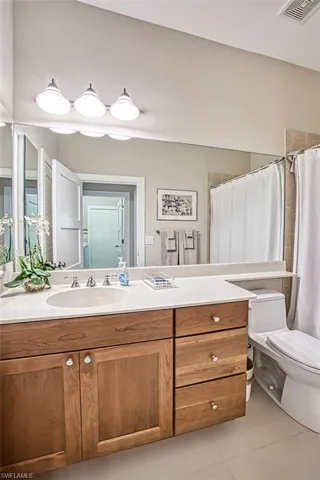 Bathroom with vanity, toilet, curtained shower, and tile patterned flooring