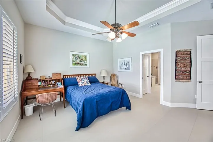 Bedroom with ornamental molding, ceiling fan, and a tray ceiling