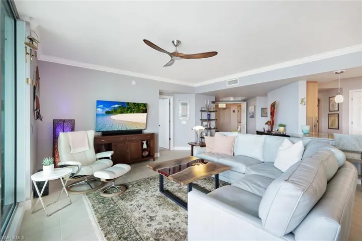 Living room featuring ceiling fan, light tile patterned floors, and ornamental molding