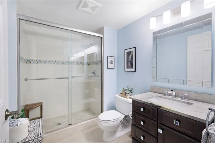 Bathroom featuring tile patterned flooring, vanity, toilet, and a shower with door