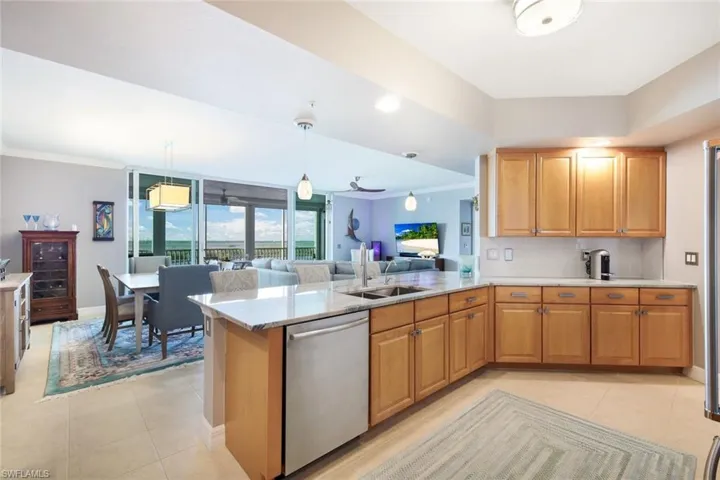 Kitchen featuring backsplash, sink, stainless steel dishwasher, decorative light fixtures, and kitchen peninsula