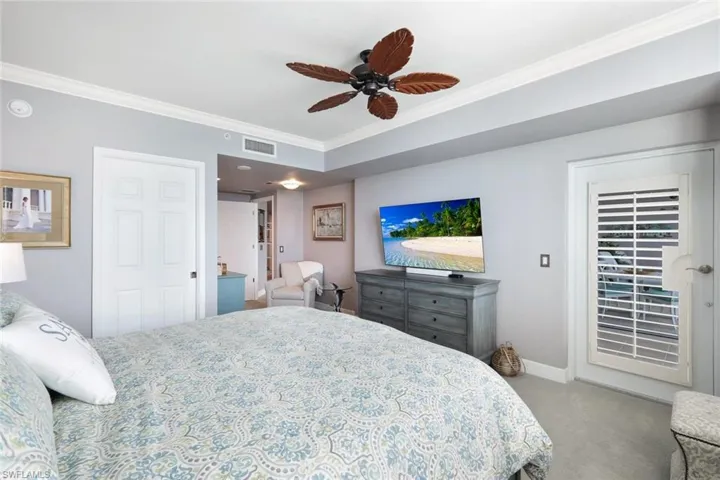 Carpeted bedroom featuring ceiling fan and crown molding