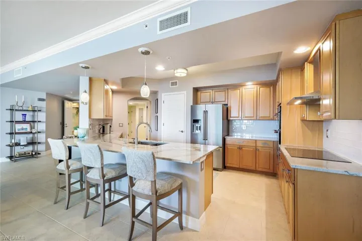 Kitchen featuring black electric stovetop, sink, stainless steel refrigerator with ice dispenser, a kitchen bar, and kitchen peninsula