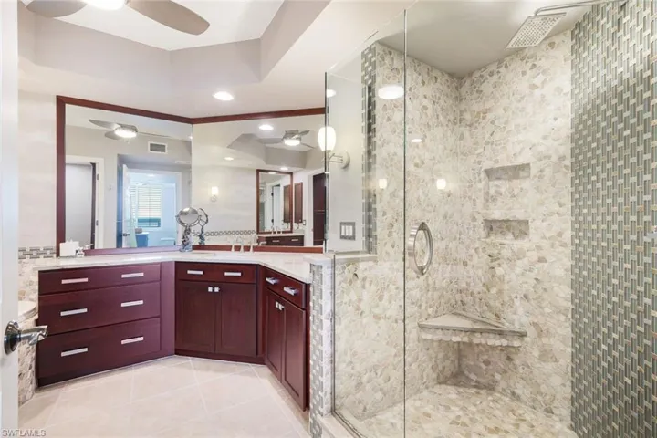 Bathroom featuring ceiling fan, tile patterned flooring, vanity, and a shower with shower door