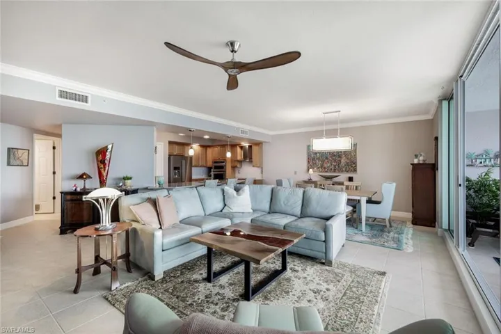 Living room featuring ceiling fan, ornamental molding, and light tile patterned floors