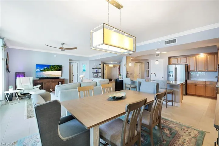 Dining room with light tile patterned floors, ceiling fan, and crown molding