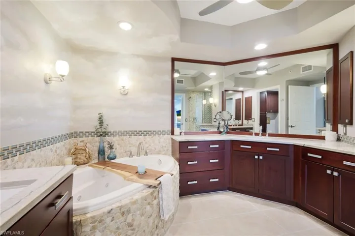 Bathroom with vanity, tiled bath, and a raised ceiling
