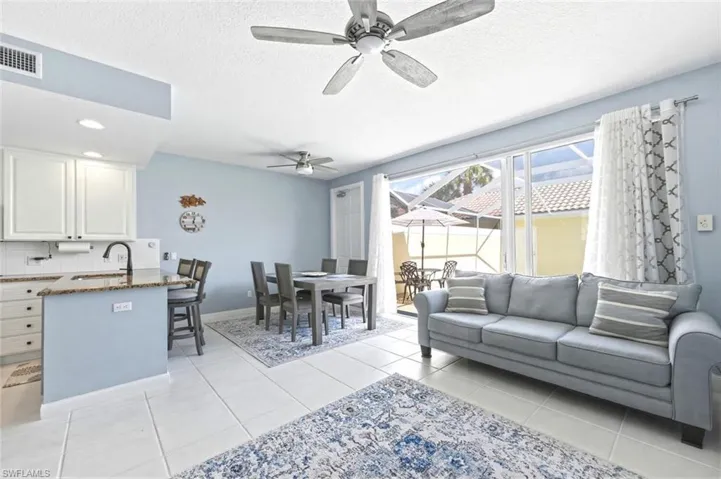 Living room featuring ceiling fan, light tile patterned floors, and a textured ceiling