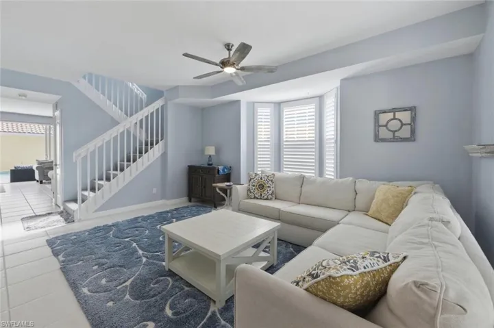 Tiled living area featuring a ceiling fan and stairs
