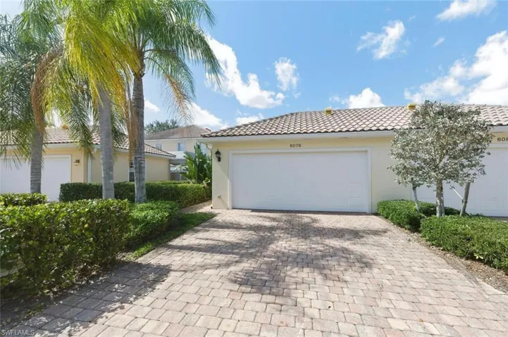 View of front of house featuring a tile roof, stucco siding, a garage, and decorative driveway