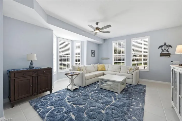 Living room featuring ceiling fan, plenty of natural light, and light tile patterned flooring