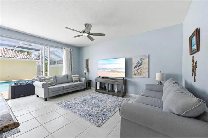 Tiled living area featuring ceiling fan and a textured ceiling
