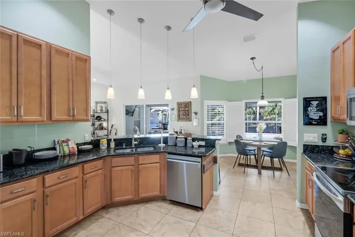 Kitchen featuring wood cabinetry, dark granite countertops, stainless steel appliances, and a tile backsplash