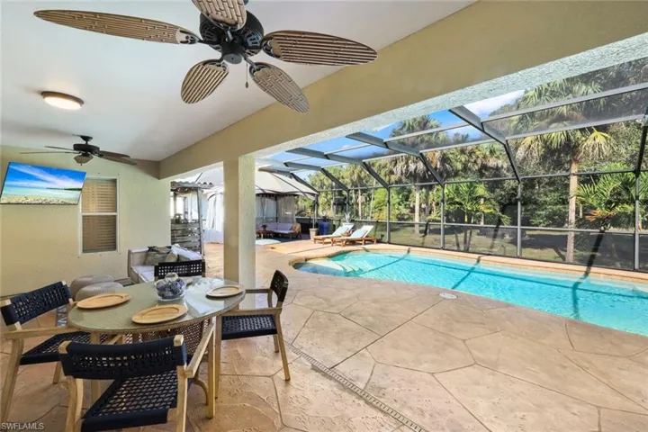 Screened-in lanai with a swimming pool, textured concrete decking, and a covered patio