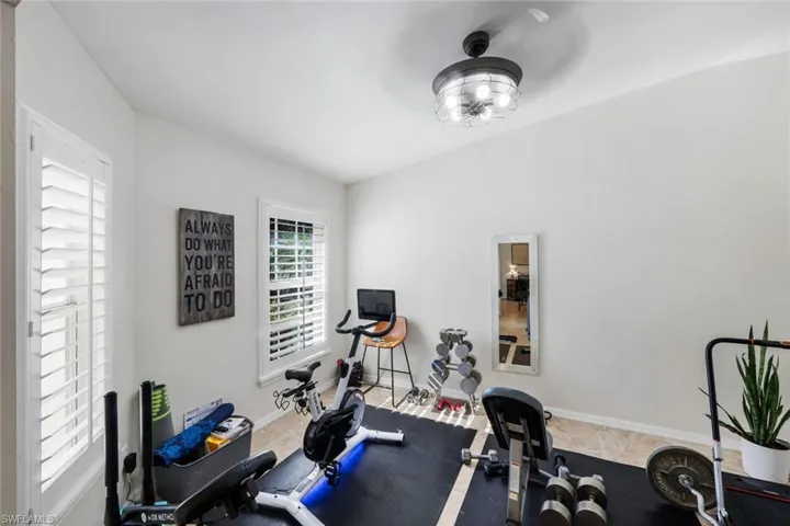 Versatile room featuring two windows with white plantation shutters, a modern ceiling light fixture, and neutral wall tones