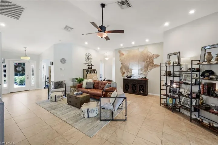Spacious interior featuring a vaulted ceiling with recessed lighting, large format tile flooring, a prominent ceiling fan, and a double-door entry with sidelights