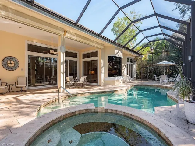 View of pool and hot tub with completely screened lanai and covered patio in the background with electric shutters.