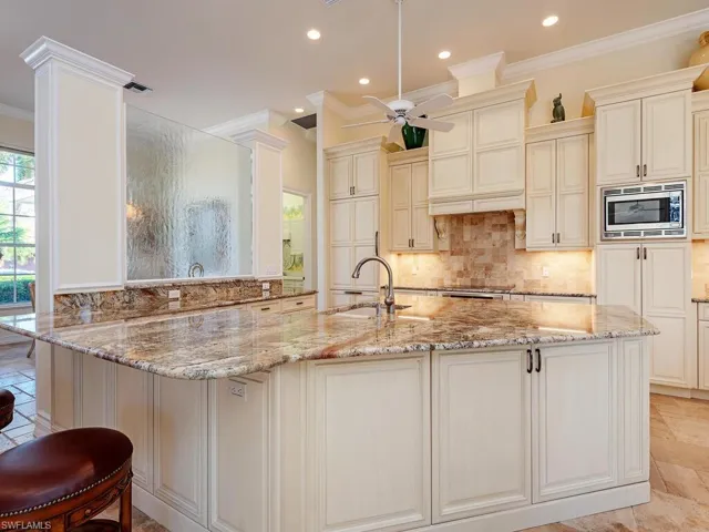 Gourmet Kitchen with sink, ceiling fan, light stone countertops, crown molding and stainless-steel appliances.