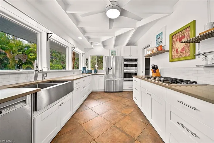 Kitchen featuring white cabinetry, stainless steel appliances, ceiling fan, and tasteful backsplash