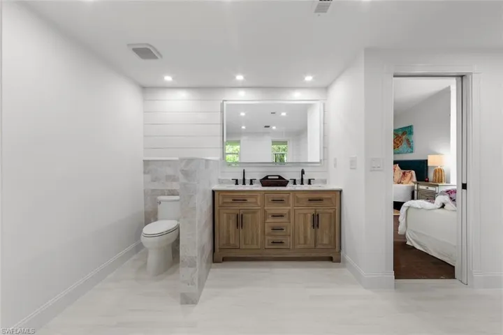 Bathroom featuring toilet, vanity, tile walls, and wood-type flooring